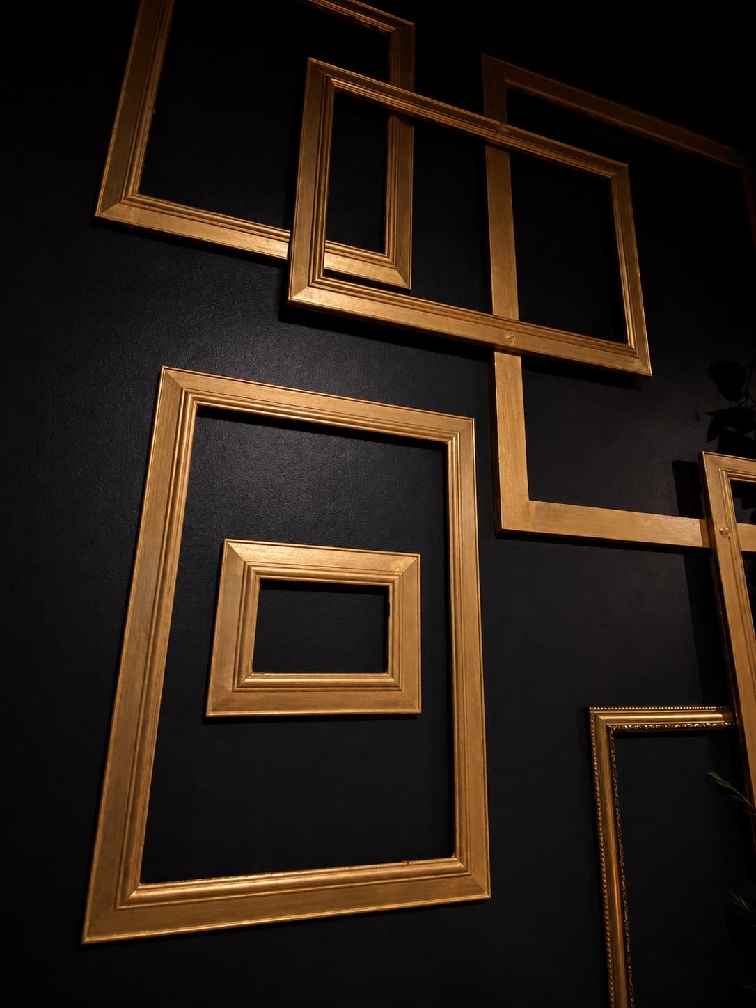 Overlapping gold picture frames on the black wall of the Cocktail Lounge