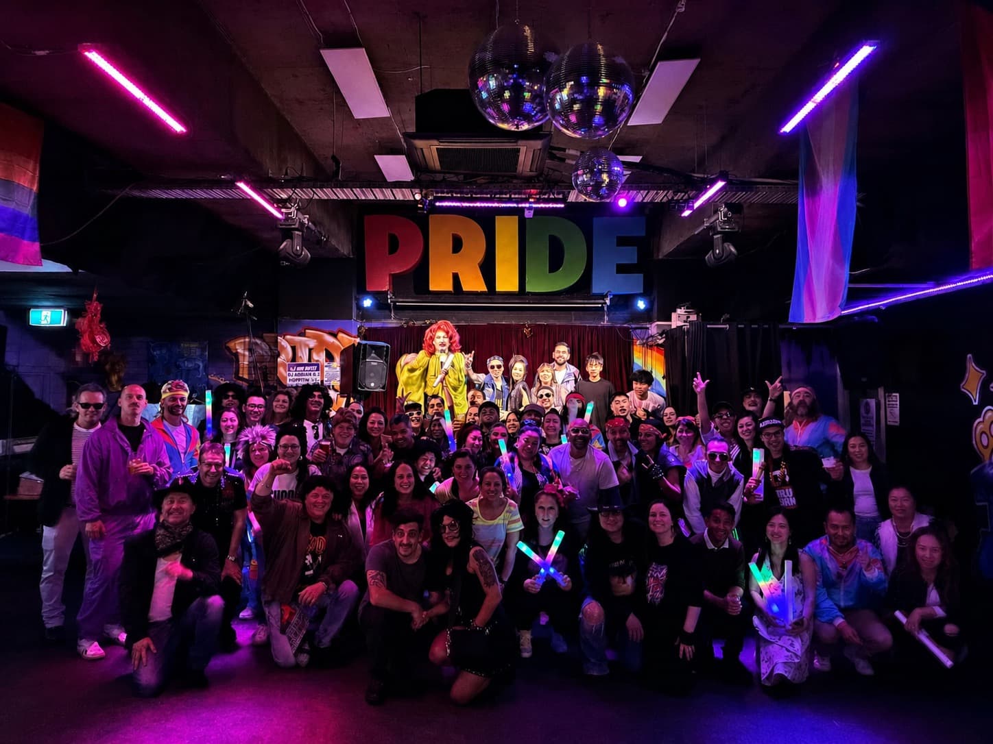 Crowd posing for a group photo in front of the PRIDE stage at Pride of our Footscray